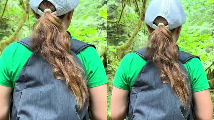 麦克米伦省立公园一个十几岁的女孩站在一棵大树旁，她穿着绿色的t恤和黑色的牛仔裤，戴着帽子，背着背包，