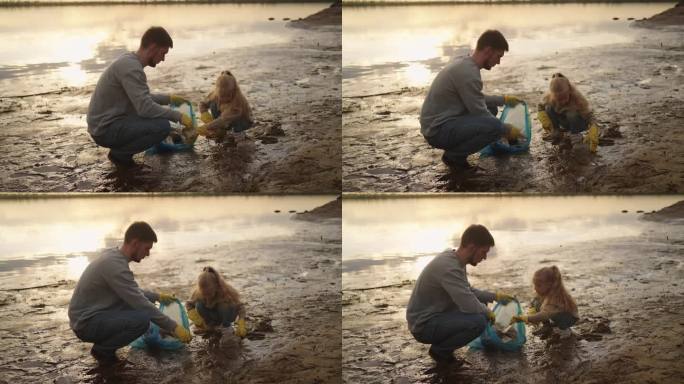 父亲和女儿清理海岸的塑料垃圾，击掌庆祝胜利