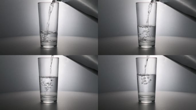 干净的饮用水从玻璃瓶里倒进桌子上的玻璃杯里，桌子的背景是灰色的，背光很漂亮。气泡水健康的营养。水就是