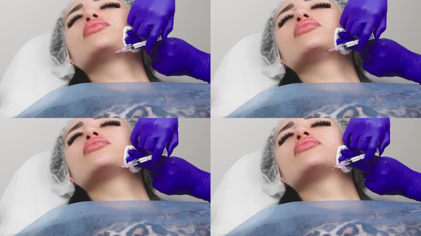 一位美容师正在给一位女士的下巴、嘴唇下面的皮肤注射含有透明质酸的生物活化剂(特写)。年轻女子在美容诊