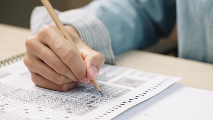 学生用手做考题，用铅笔写考题答题卡，根据考试概念回答考题