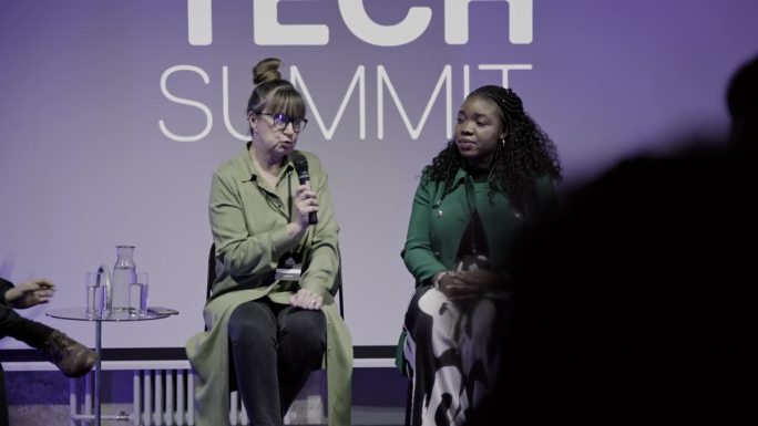 女采访者在舞台上向科技企业家提问。