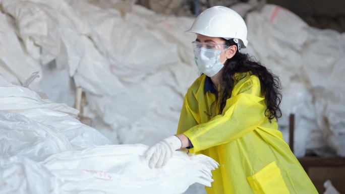 戴口罩的黑头发女工在垃圾处理厂拣垃圾