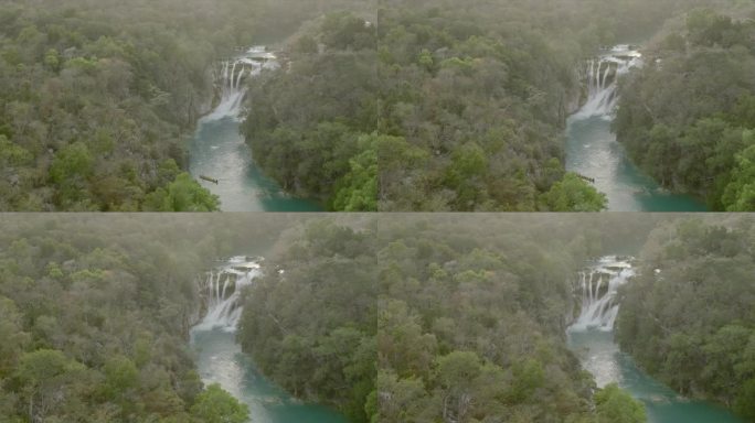 空中无人机观看瀑布和流经茂密丛林的河流