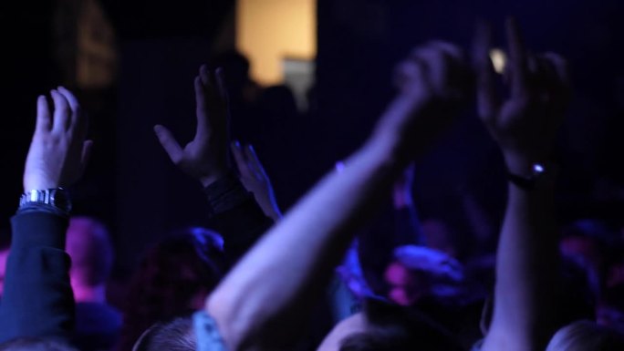 欢呼雀跃的年轻人在免费音乐会上跳起舞来，举手示意