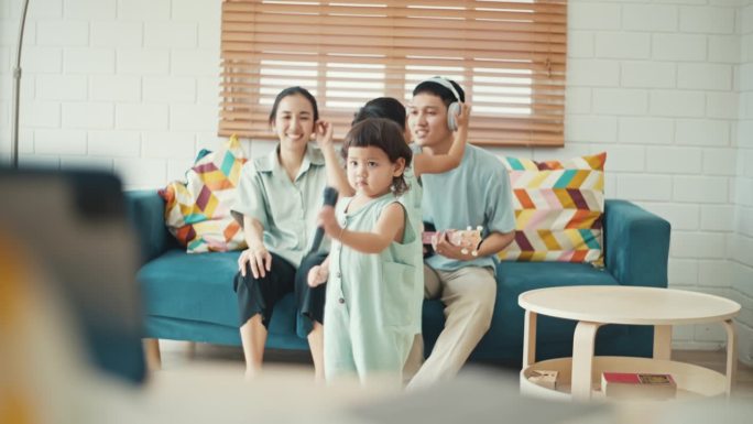 快乐的亚洲家庭在家里唱歌跳舞
