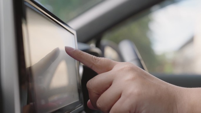 一个人触摸汽车仪表盘的多媒体触摸屏来查看地图gps或控制音乐收音机准备开车