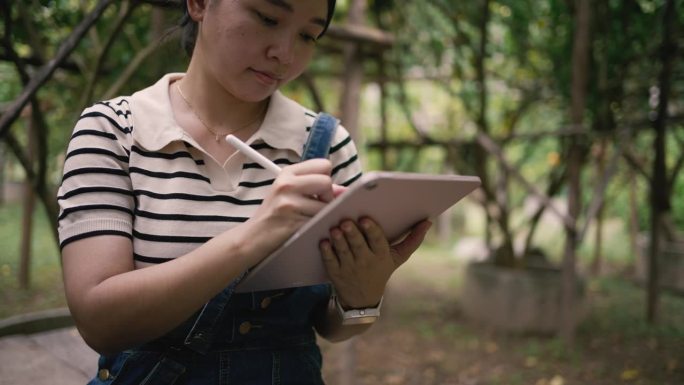 一名年轻女子在农场检查庄稼时使用数字平板电脑。做最有利于农产品质量增长的事。