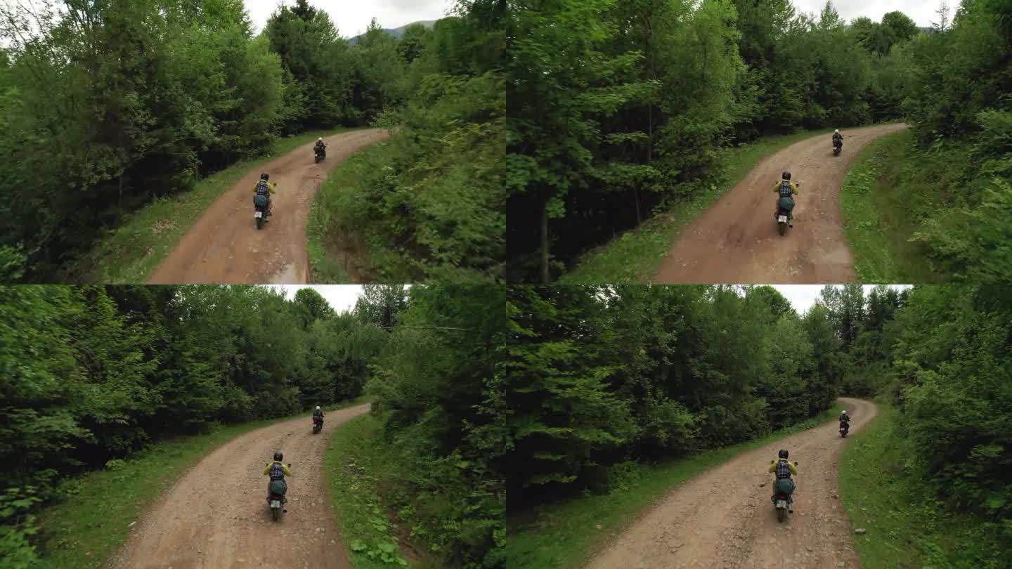两名摩托车手骑着土路穿过森林，鸟瞰图