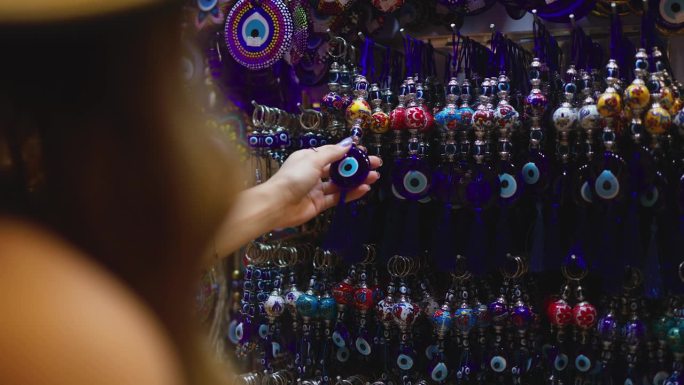 年轻的女游客在伊斯坦布尔大巴扎检查邪眼珠，在伊斯坦布尔检查纪念品，护身符对抗邪眼珠，邪眼珠
