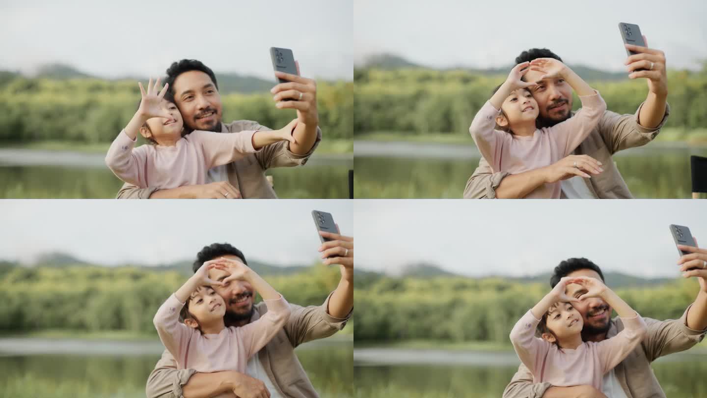 度假时在草地上露营，一对快乐的父亲和女儿微笑着坐在相机前拍照。