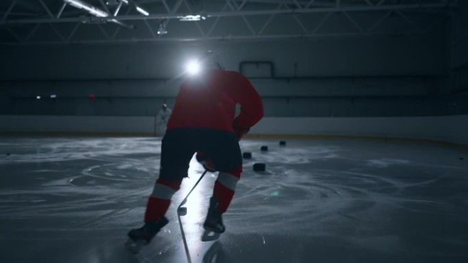 一段令人兴奋的视频片段，一名身穿红色运动衫的冰球运动员在黑暗的冰场上训练，展示了快速的动作和专业的技