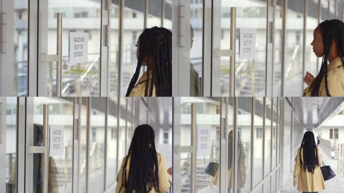 一名非裔美国妇女在医院玻璃门上读出疫苗缺货的标志