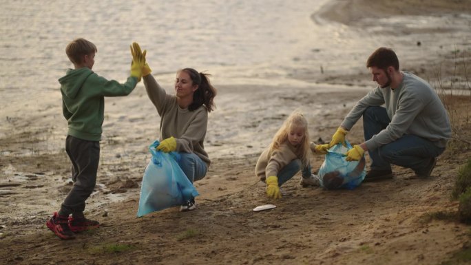 孩子和家长清理河岸垃圾，生态理念，家庭周末在大自然