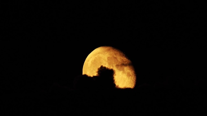 巨大的橙色月亮在云后移动