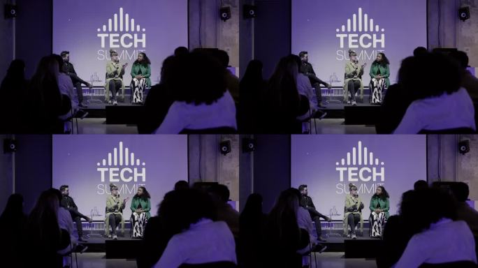 女采访者在舞台上向科技企业家提问。