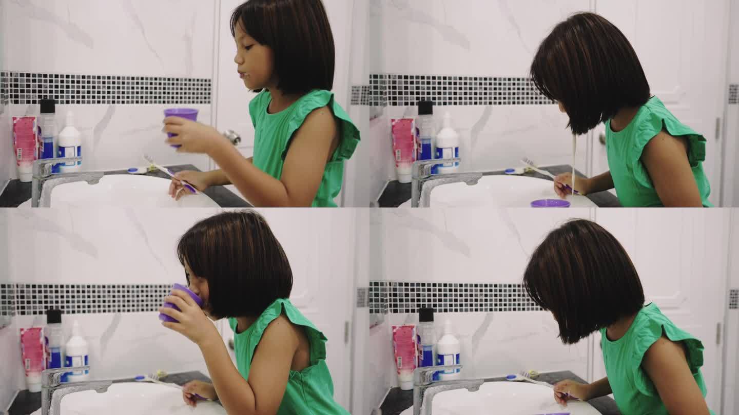 小女孩在浴室的水池边刷牙。