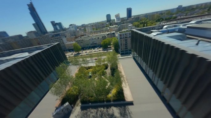 在阳光明媚的日子里，第一人称无人机在现代城市景观中观看大型工厂建筑屋顶