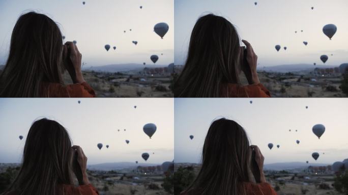 快乐的年轻高加索女游客用胶片相机拍下了令人难以置信的热气球。