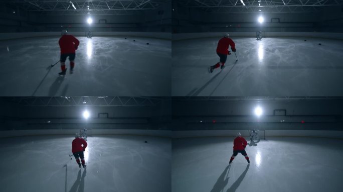 一名熟练的冰球运动员身穿红色运动衫，在黑暗的冰场上训练，快速移动并向守门员进球
