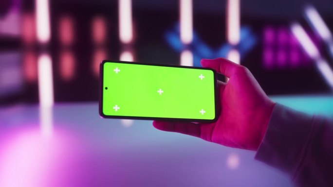 玩家在智能手机上查看社交网络帖子，模拟绿屏Chromakey显示屏。一个人在未来的霓虹灯房间里水平拿