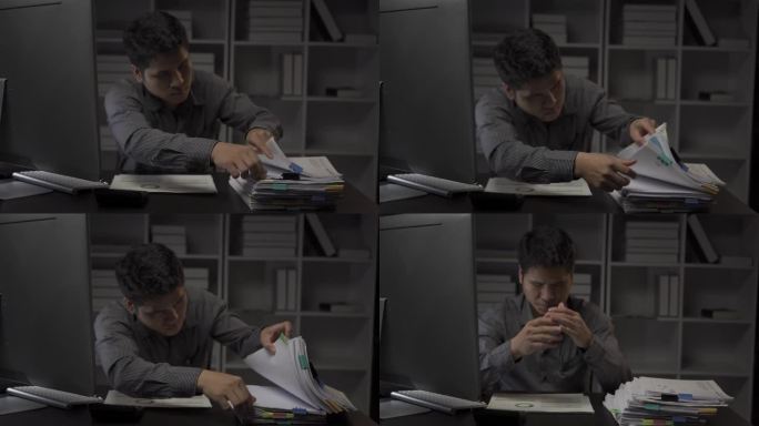 亚洲男性商人在办公室用财务文件和台式电脑工作到很晚，加班的年轻人工薪族概念4k