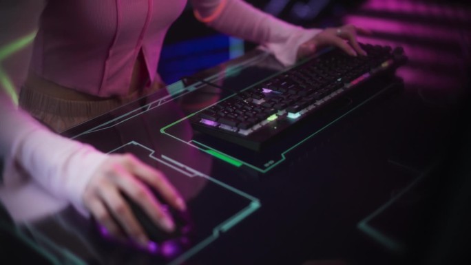 女玩家坐在彩色霓虹灯工作室的未来互动桌后。年轻女子使用键盘和鼠标在桌子上与科技动画。游戏内容的素材