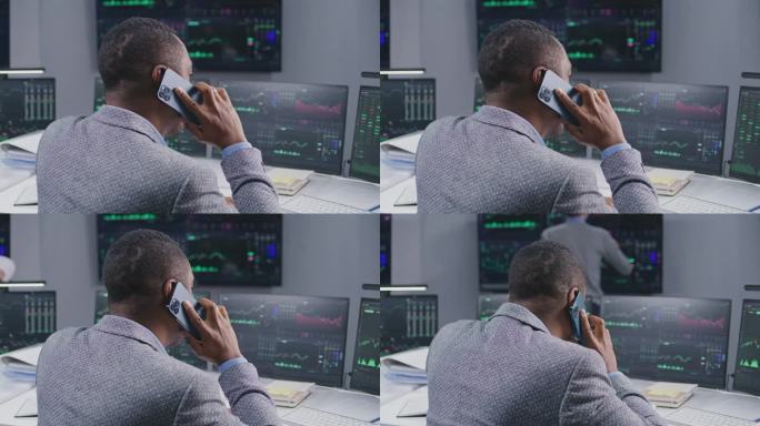 非裔美国男性股票交易员通过电话交谈，在经纪人办公室工作