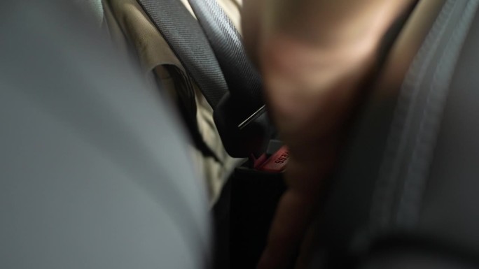 细节裁剪镜头，无法辨认的男性司机停车，解开安全带。男司机解开汽车安全带的特写镜头。