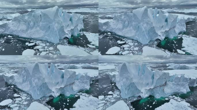 在格陵兰岛伊卢利萨特附近的巨大冰山附近飞行。冰山碎块掉入水中。空中北极自然景观，全球变暖和气候变化的