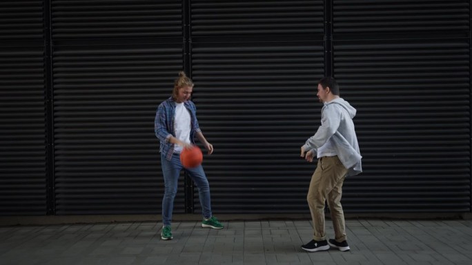患有唐氏综合症的男子和他的朋友在户外打篮球。友谊的概念和残疾人融入社会。