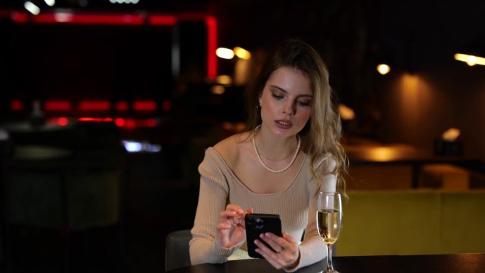 年轻漂亮的女人坐在餐厅里看留言。惊讶的女士看着手机屏幕。生活方式的概念。慢动作