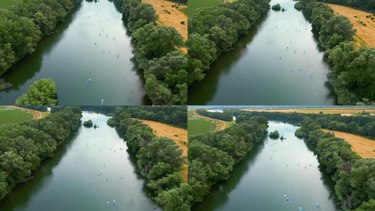 在摩尔多瓦的德涅斯特，无人机拍摄了多人站立冲浪的画面。河两岸是郁郁葱葱的森林