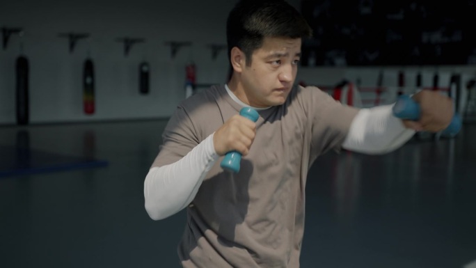 亚洲拳击手在拳击馆里用哑铃单独练习的慢动作