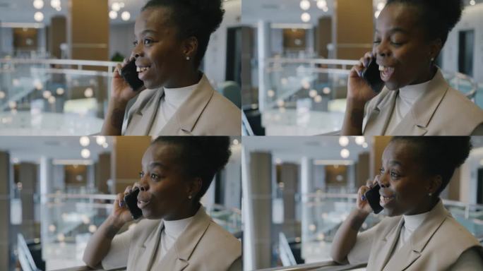 兴奋的非裔美国女商人在灯火通明的酒店大堂用手机聊天，面带微笑