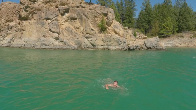 人从岩石上跳水，游过湖泊
