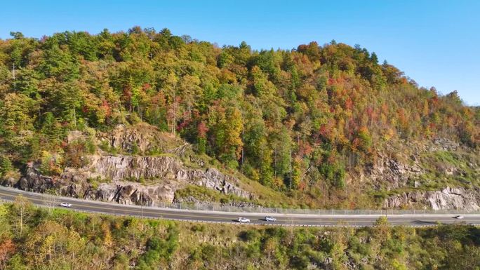 北卡罗莱纳州宽阔的高速公路通往阿巴拉契亚山脉，那里有黄色的秋天森林和快速移动的交通。美国国家公园内的