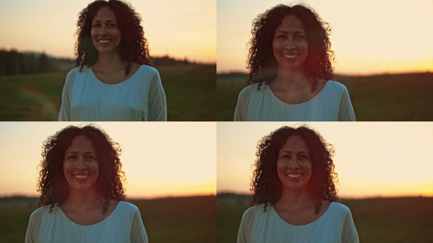 一个女人在日落时在草地上微笑的肖像