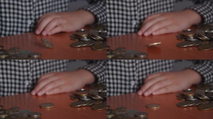 人类的双手转动硬币，它就会在桌子上旋转。算命，正反，巧合，机会。金融知识的概念。不知名的小女孩穿着格