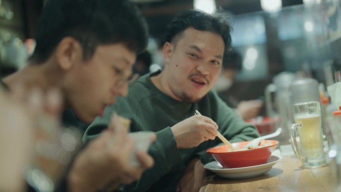 两个亚洲人在日本餐馆吃一碗日本荞麦面。