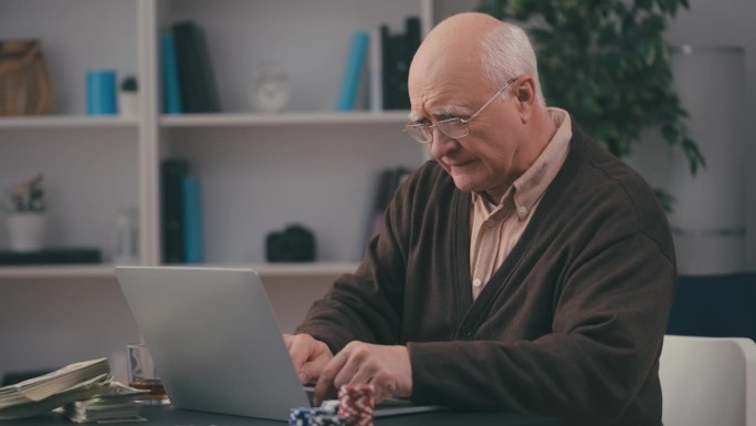 老人在家里用笔记本电脑玩在线扑克，赌博