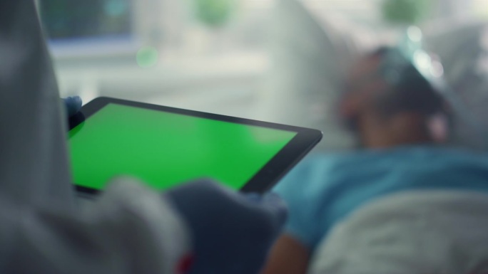 医生使用pad色度键屏幕特写。病床上病人的氧气面罩