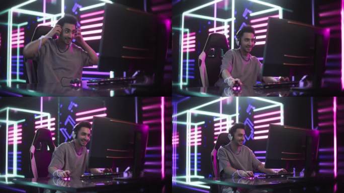 手持缩放镜头的一个兴奋的男性玩视频游戏在电脑上在线。英俊的玩家戴上耳机，与网友和玩家交谈。流媒体和游