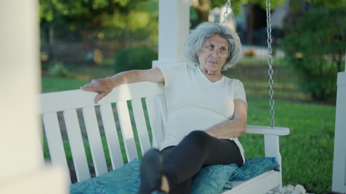 一位年长的德国妇女坐在后院的秋千上沉思着