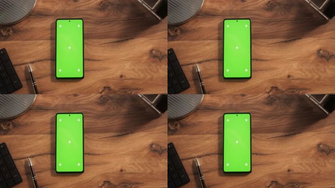 智能手机的顶视图与模拟绿色屏幕显示。设备垂直放置在木制办公桌上的静态画面。在线数字营销和内容创作模板