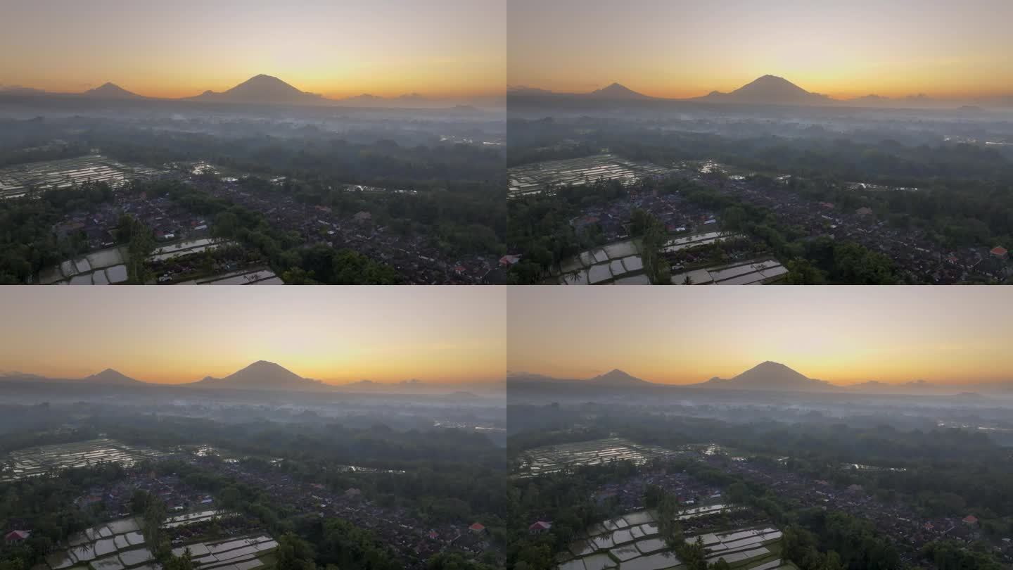 空中无人机拍摄的印尼巴厘岛丛林中，以阿贡火山为背景的高山梯田的日出景象。