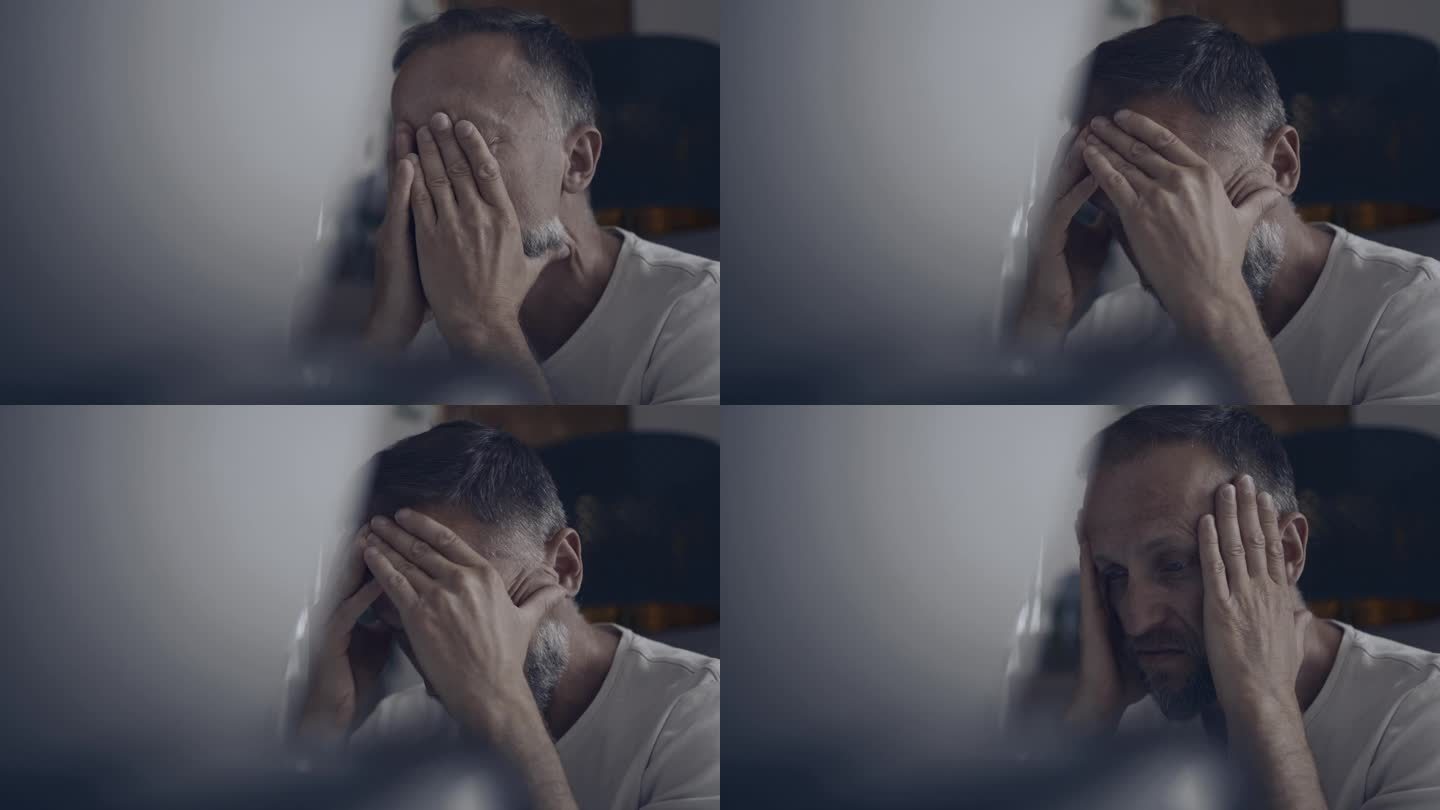 一个忧郁的男人独自坐在电脑屏幕前，双手捂着脸。工作倦怠和焦虑