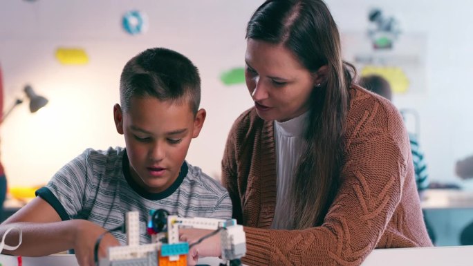 学生、老师和教育工作者在教室里一起学习和帮助机器人。学习，机器人和孩子与科学的女人教孩子工程，技术和