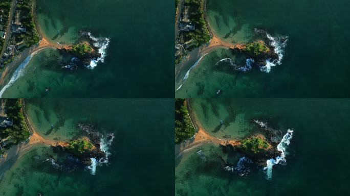 绿色的热带岩石岛，在蓝绿色的海洋中间，被海浪冲刷着。无人机拍摄的画面显示，斯里兰卡米瑞萨的鹦鹉岩被波