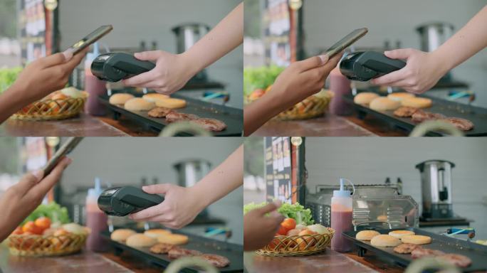 一位顾客在餐车上买了一个美味的汉堡，用智能手机付款。非接触式支付。申请网上银行付款。非接触式技术。A